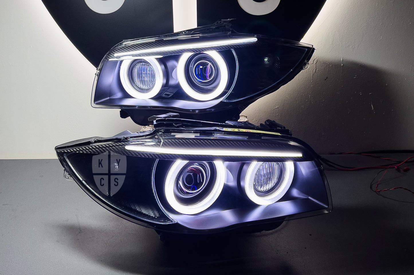 BMW 1 Series E87 & E81 E82 E88 (Pre LCI Xenon/Adaptive Xenon) Custom Headlights. Equipped With The Following Options: BavGruppe Design Round Angel Eyes (White) | BavGruppe Design Carbon Fibre Eyebrow With Optic & LED Strip (White) | G5-BRT Projector & Brackets (Projector Upgrade) | New Headlight Lenses