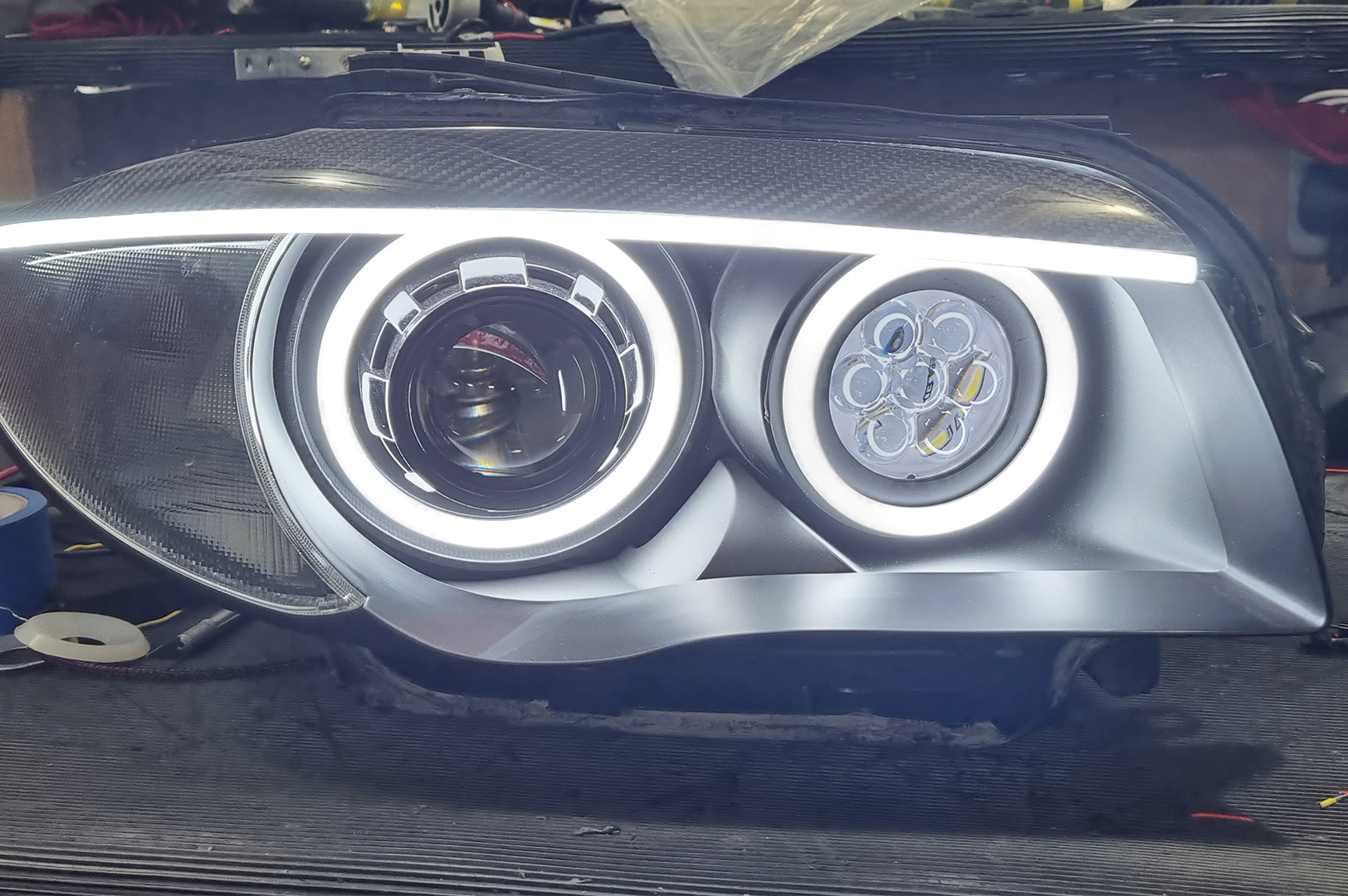 BMW 1 Series E87 & E81 E82 E88 (Pre LCI Halogen) Custom Headlights. Equipped With The Following Options: KYCS Round Angel Eyes (White) | BavGruppe Design Carbon Fibre Eyebrow With LED Strip (White) | Bi-LED Projector | LED High Beam Array